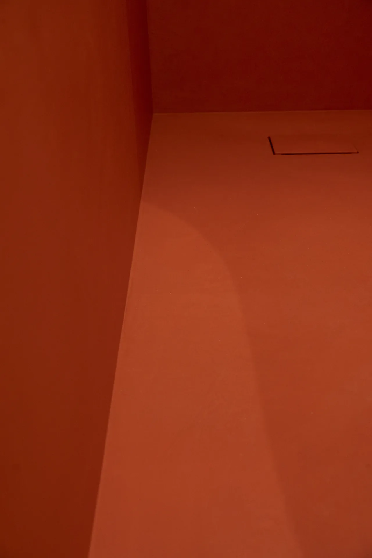 Angle béton ciré terracotta — lumière rasante