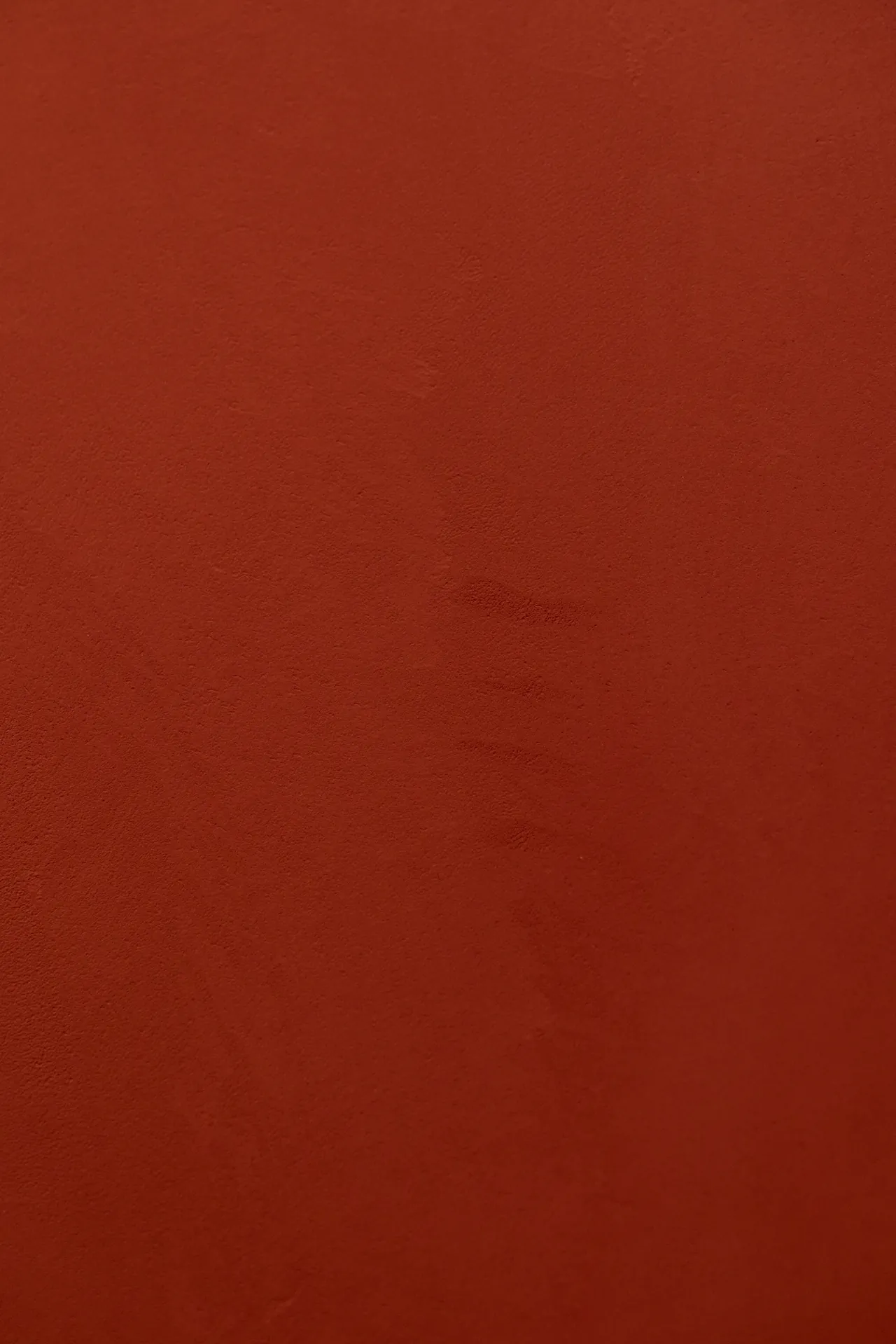 Texture béton ciré terracotta de près — grain et coups de spatule visibles