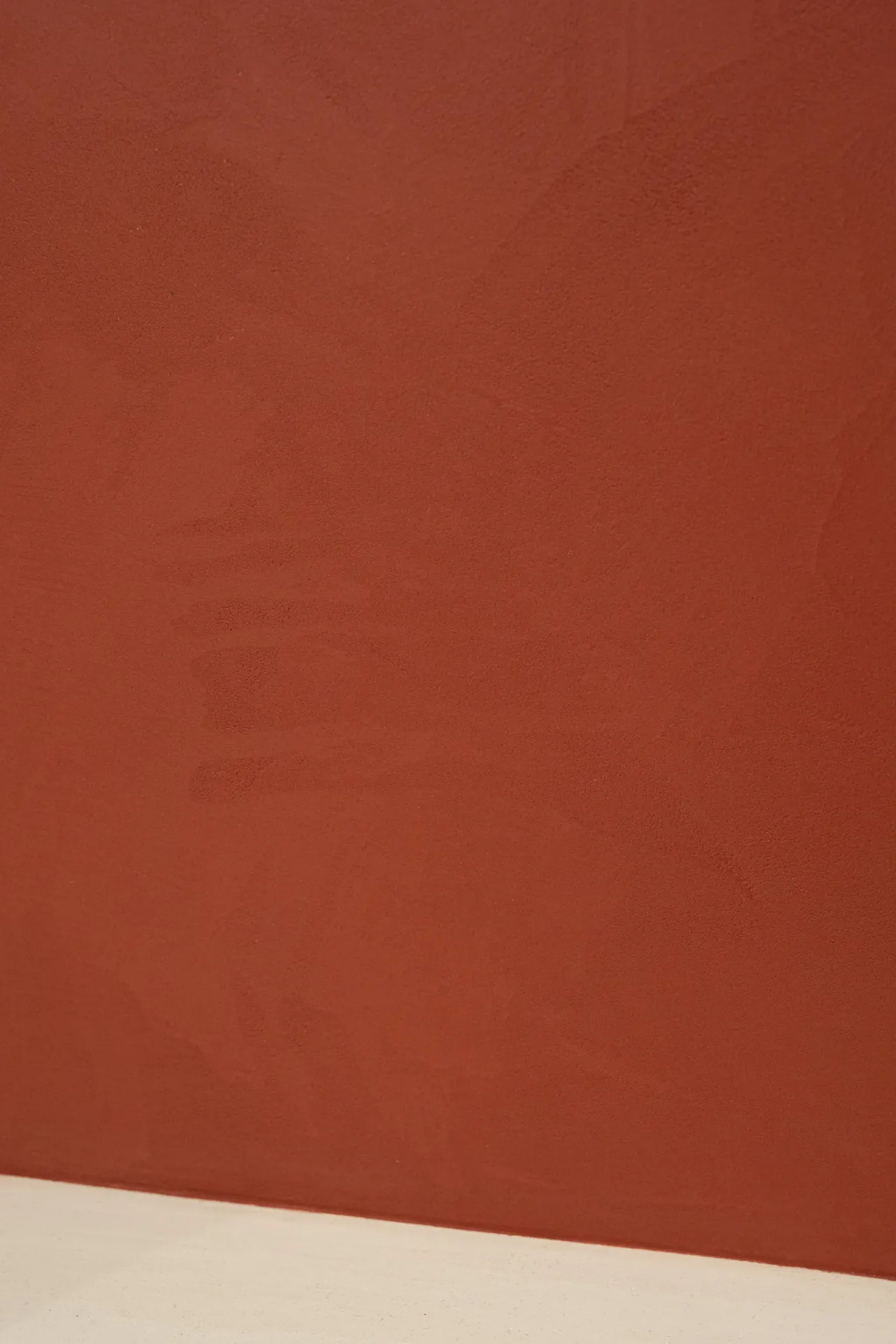 Mur béton ciré terracotta avec plinthe blanche