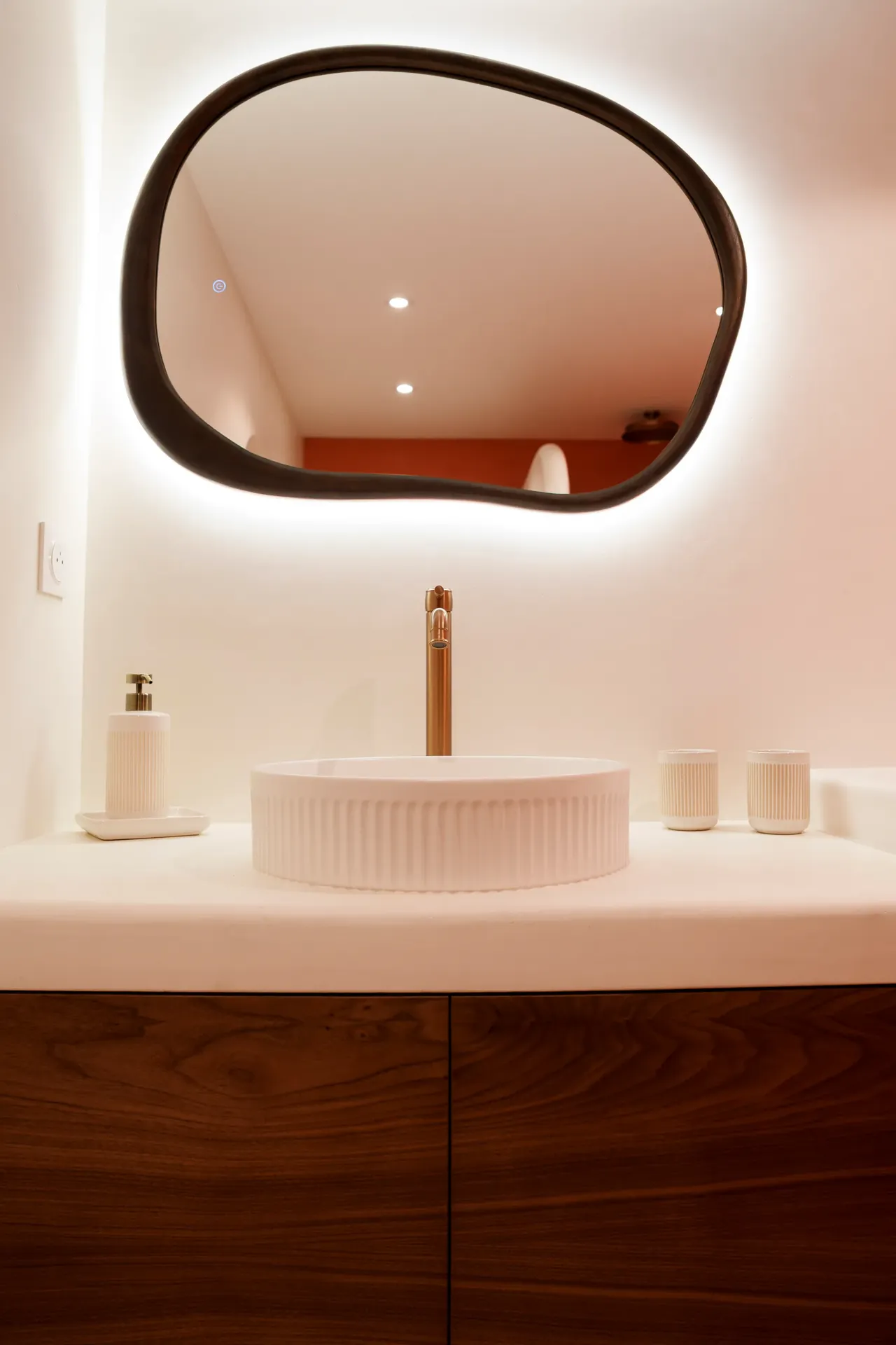 Salle de bain rénovée sur mesure par DOD& — vasque béton ciré, miroir organique et robinetterie cuivre