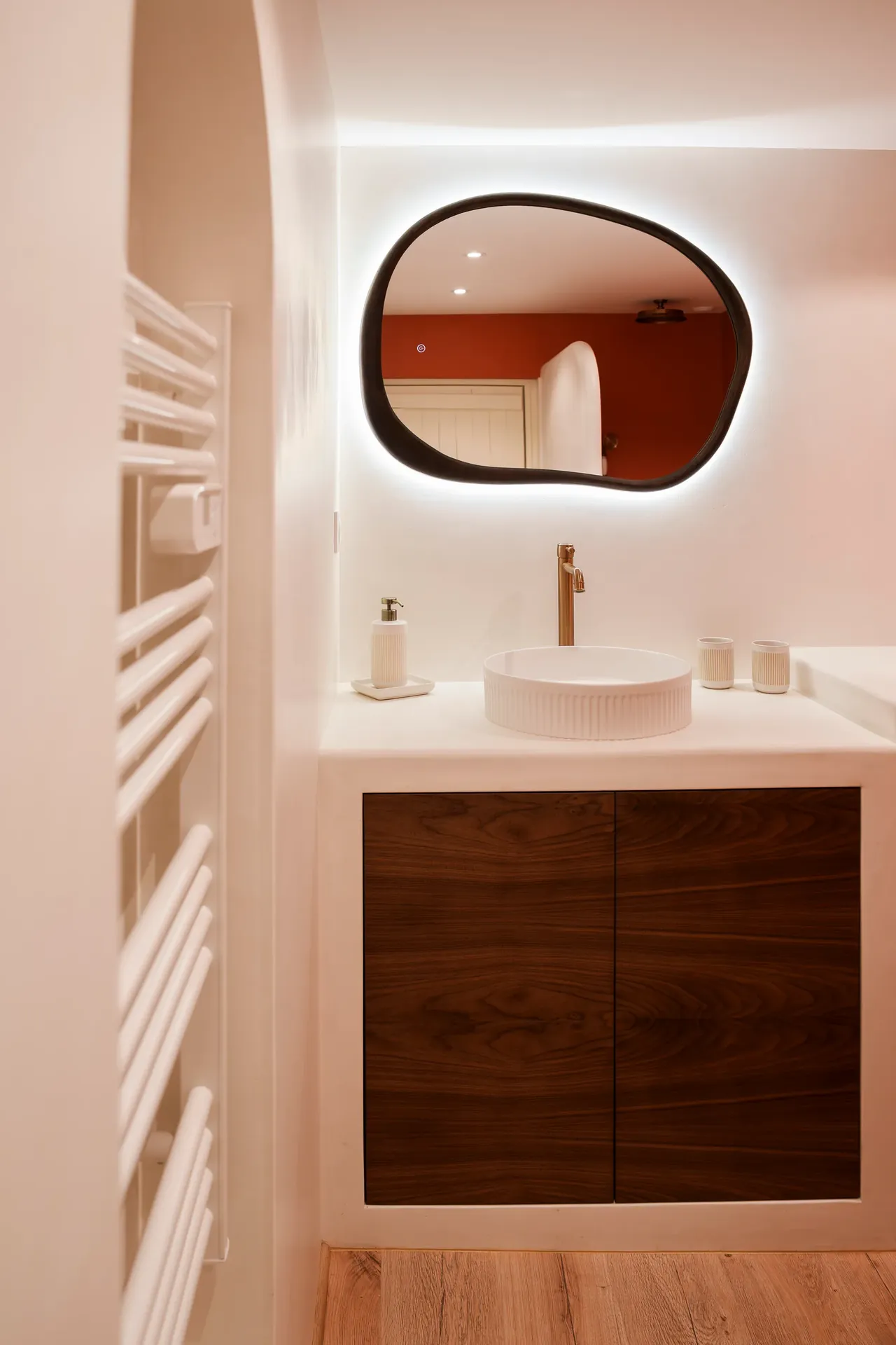 Salle de bain rénovée sur mesure — vasque, miroir organique, hublot et mur béton ciré